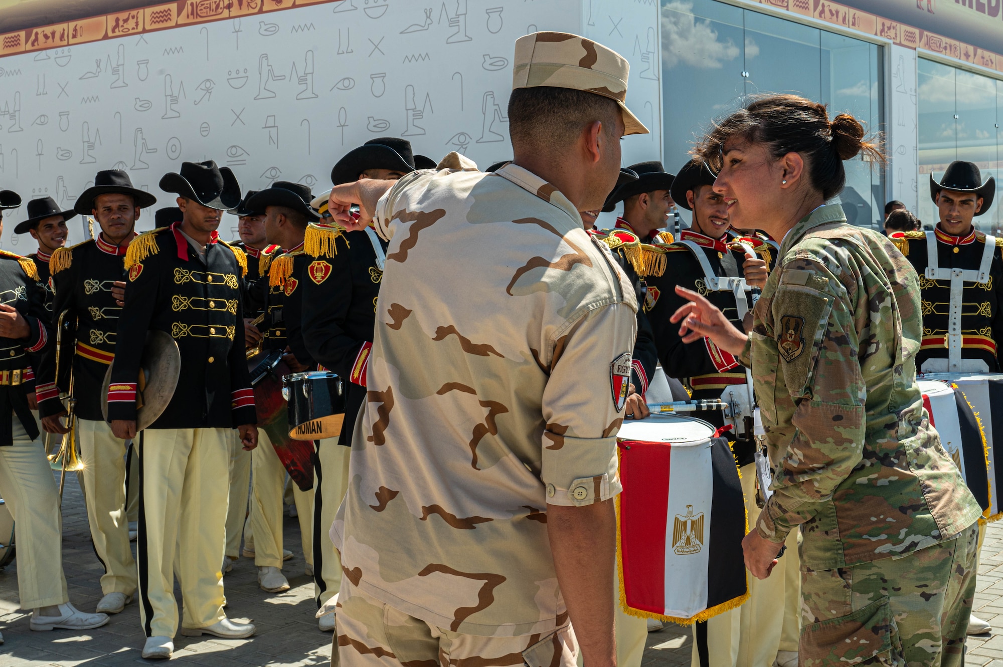 U.S. Air Force Senior Airman Amal Djezzar, 378th Air Expeditionary Wing Host Nation Coordination Cell linguist and contracting specialist, speaks with an Egyptian military service member at the Egypt International Airshow, Sept. 4, 2024. Djezzar’s knowledge of Arabic and cultural nuances has proved essential throughout her deployment, from formal negotiations to day-to-day operations. (U.S. Air Force photo)