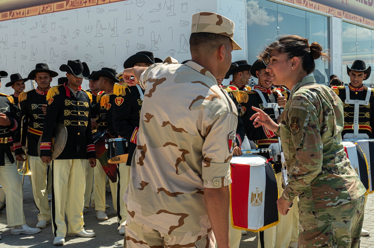 U.S. Air Force Senior Airman Amal Djezzar, 378th Air Expeditionary Wing Host Nation Coordination Cell linguist and contracting specialist, speaks with an Egyptian military service member at the Egypt International Airshow, Sept. 4, 2024. Djezzar’s knowledge of Arabic and cultural nuances has proved essential throughout her deployment, from formal negotiations to day-to-day operations. (U.S. Air Force photo)