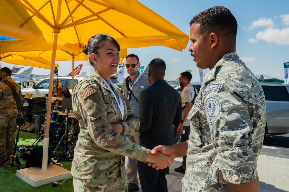 U.S. Air Force Senior Airman Amal Djezzar, 378th Air Expeditionary Wing Host Nation Coordination Cell linguist and contracting specialist, greets an Egyptian military service member at the Egypt International Airshow, Sept. 4, 2024. As a linguist, Djezzar builds trust with host nation officials, enhancing collaboration and operational efficiency. (U.S. Air Force photo)