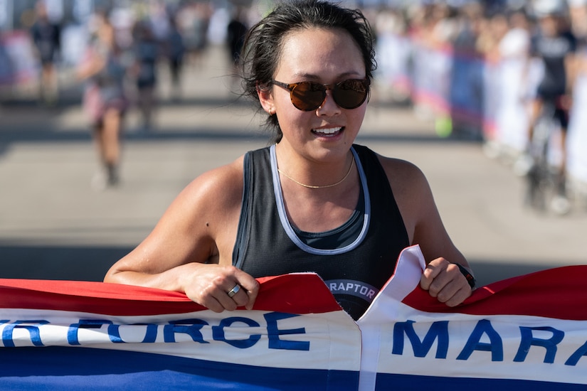 A runner breaks the tape at a marathon's finish line.