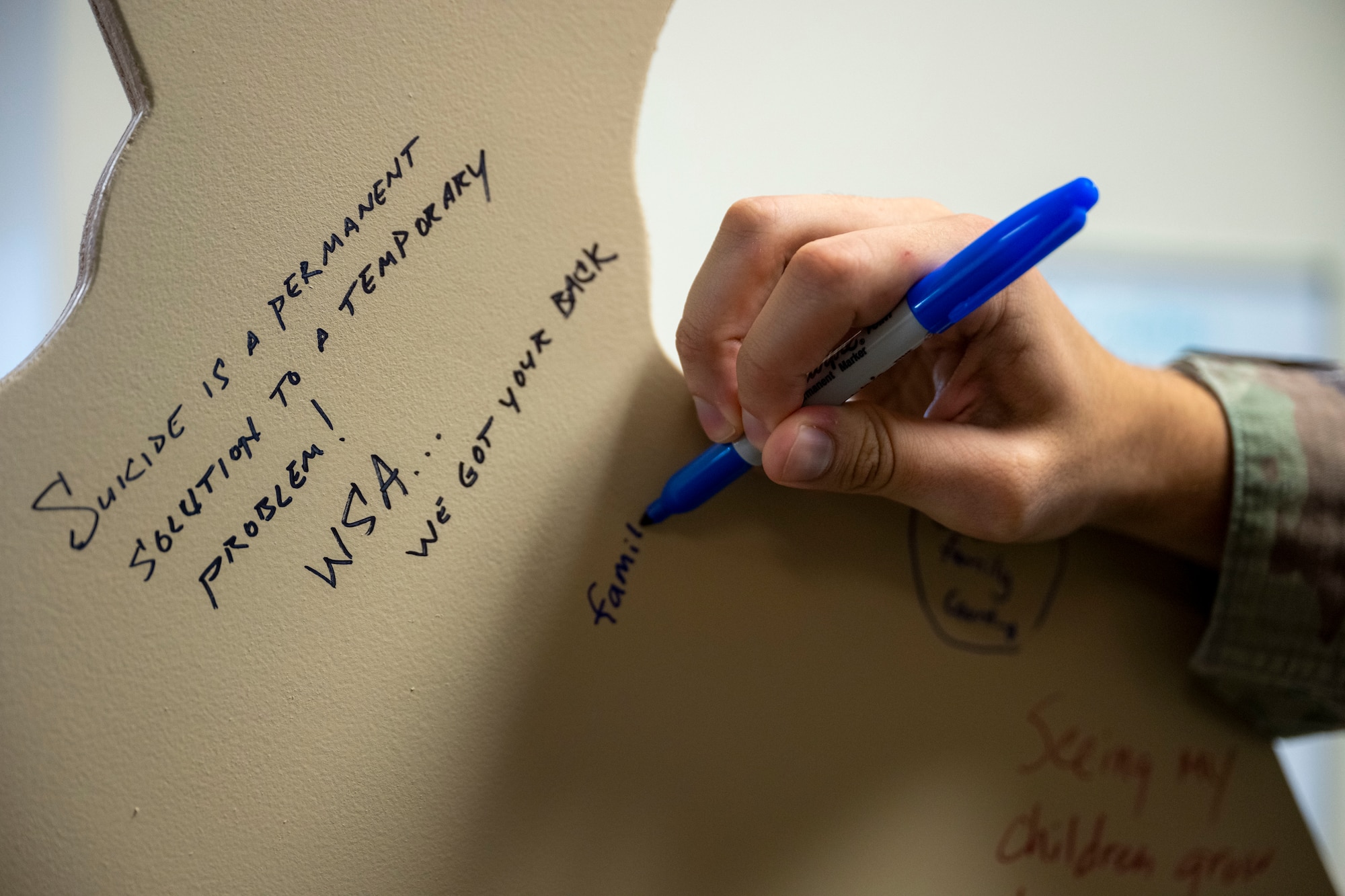 Senior Airman William Lunn, 22nd Air Refueling Wing public affairs specialist, writes his “why” on a wooden cutout for a Suicide Awareness Month exhibit at McConnell Air Force Base, Kansas, on Sept. 17, 2024. Members of Team McConnell were encouraged to write on the cutouts for display at the Robert J. Dole Center starting Sept. 18, 2024. (U.S. Air Force photo by Senior Airman Felicia Przydzial)