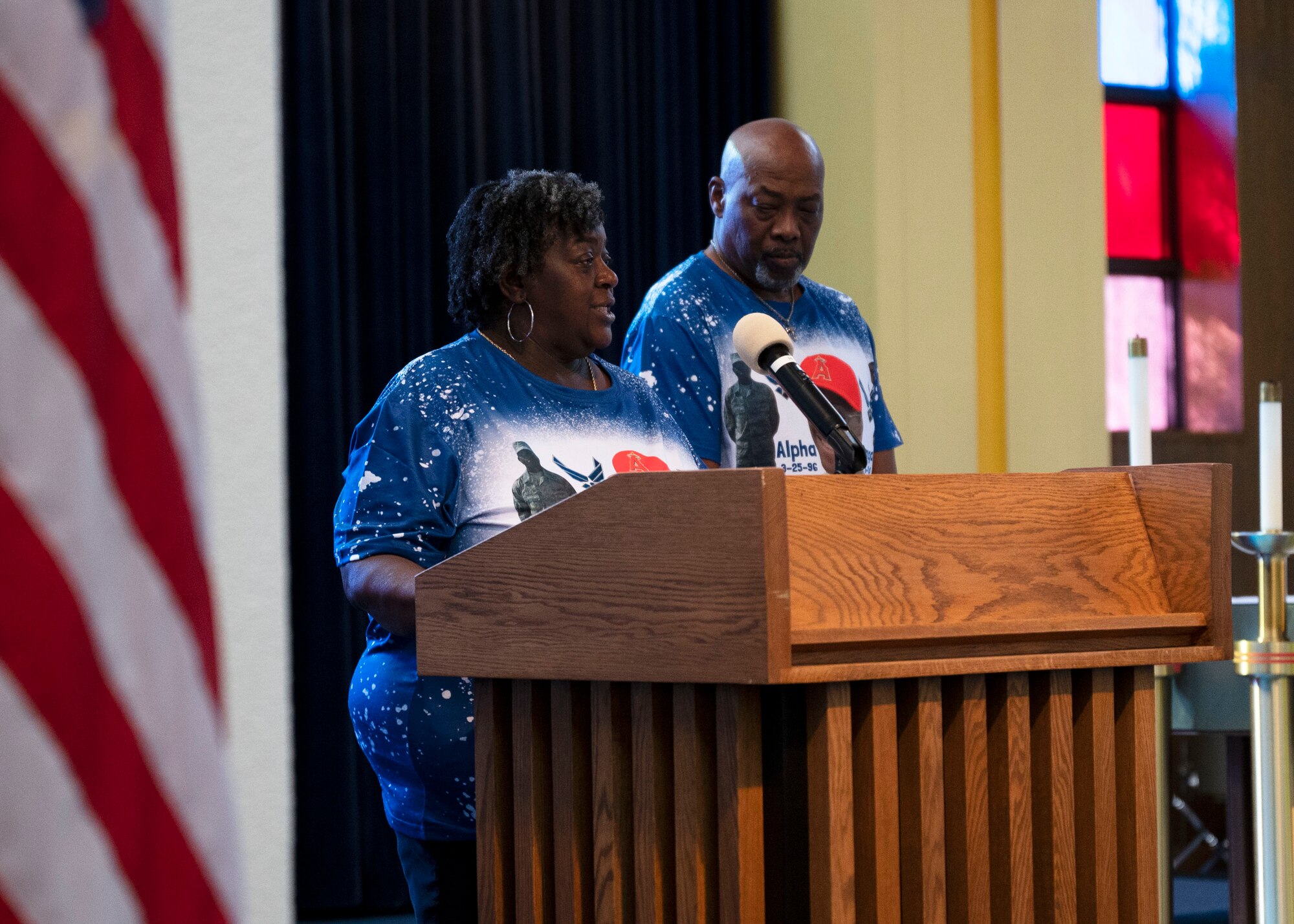 A man and woman speak behind a lectern inside a military chapel.