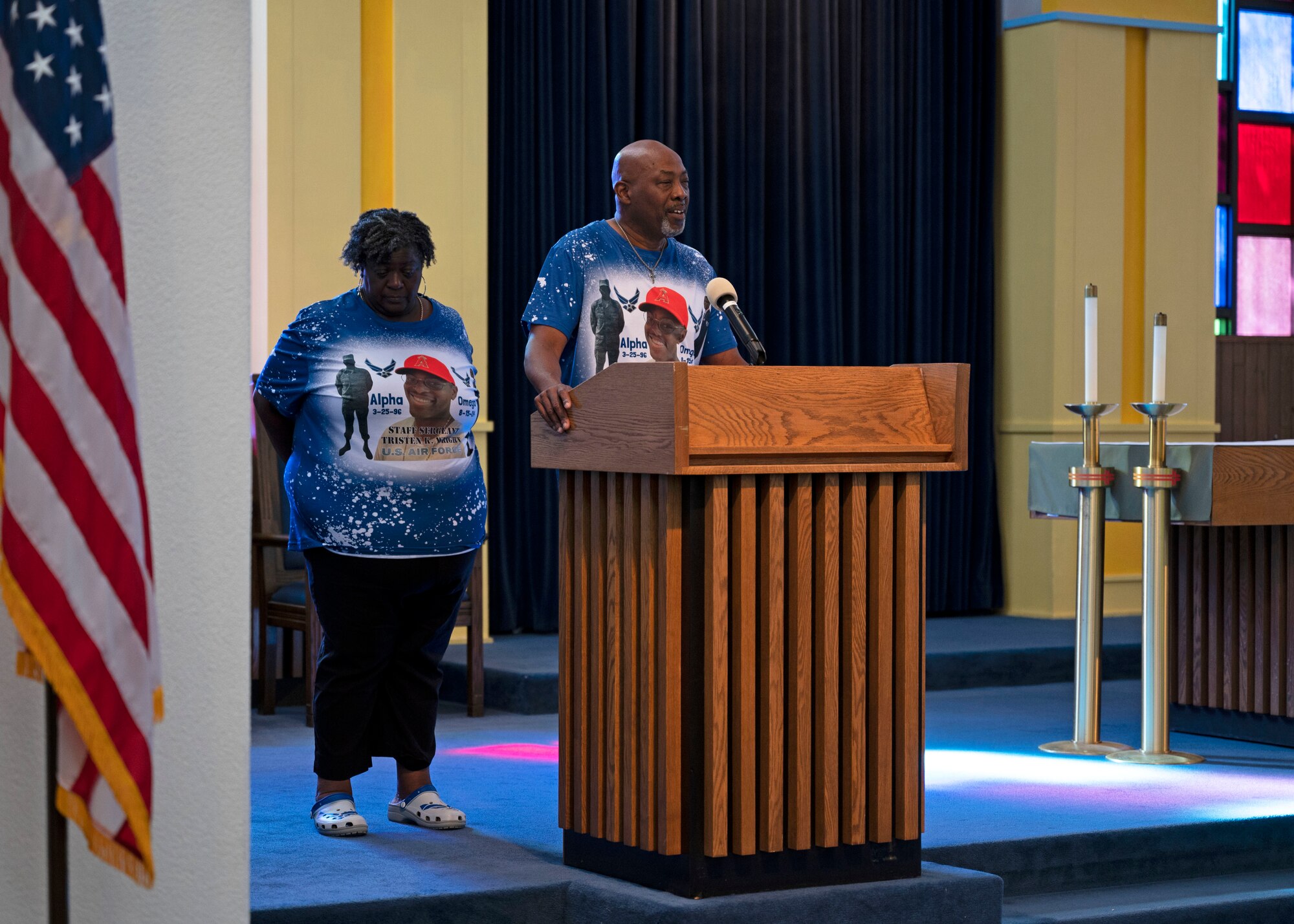 A man and woman stand behind a lectern inside a military chapel.