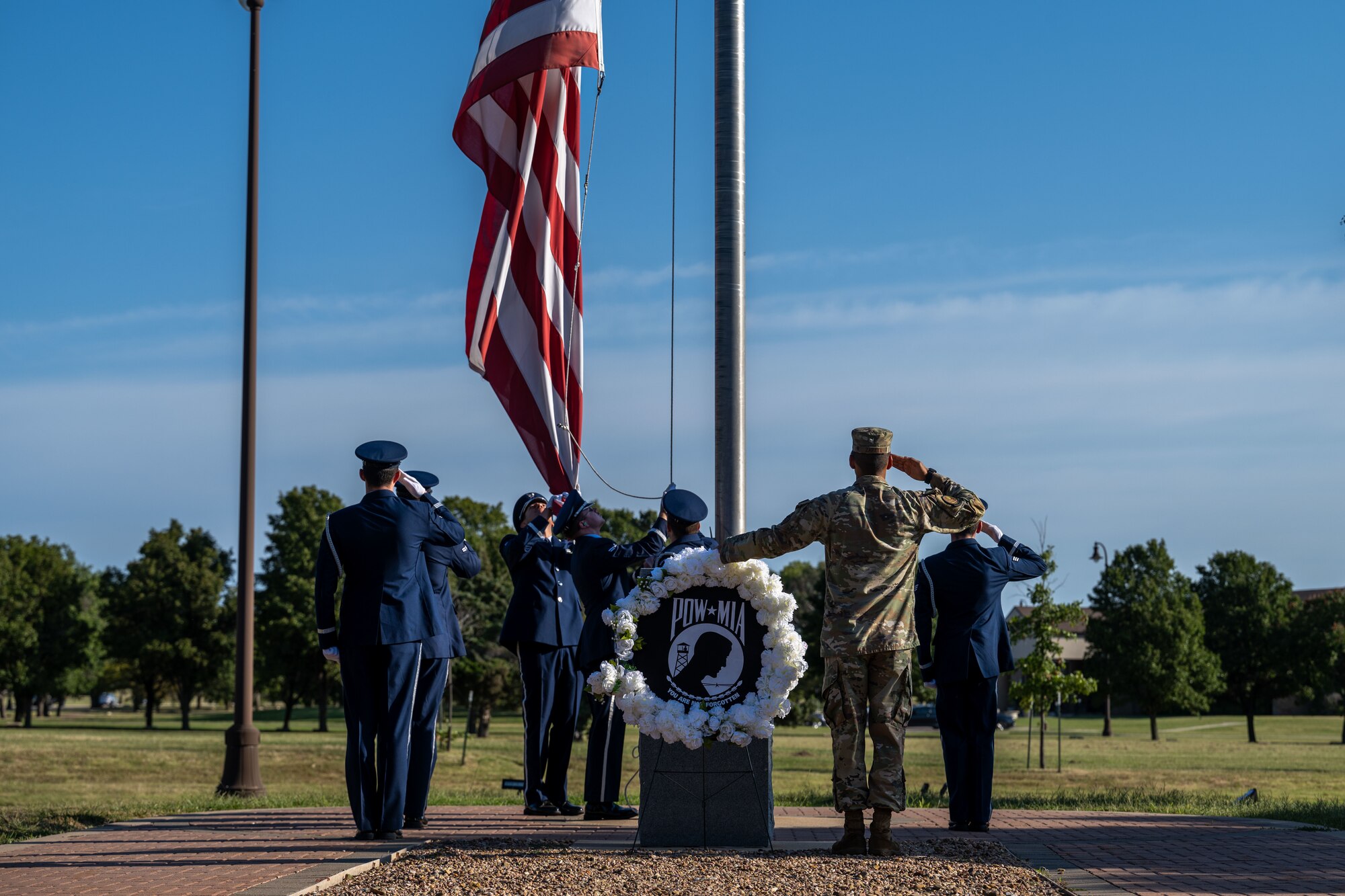 The 22nd Air Refueling Wing Honor Guard lowers the American flag during the POW/MIA week opening ceremony at McConnell Air Force Base, Kansas, Sept. 16, 2024. The wreath laying ceremony reflects commitment to finding prisoners of war actively missing and recognizes the sacrifices made by those service members and their families. (U.S. Air Force photo by Airman 1st Class Paula Arce)