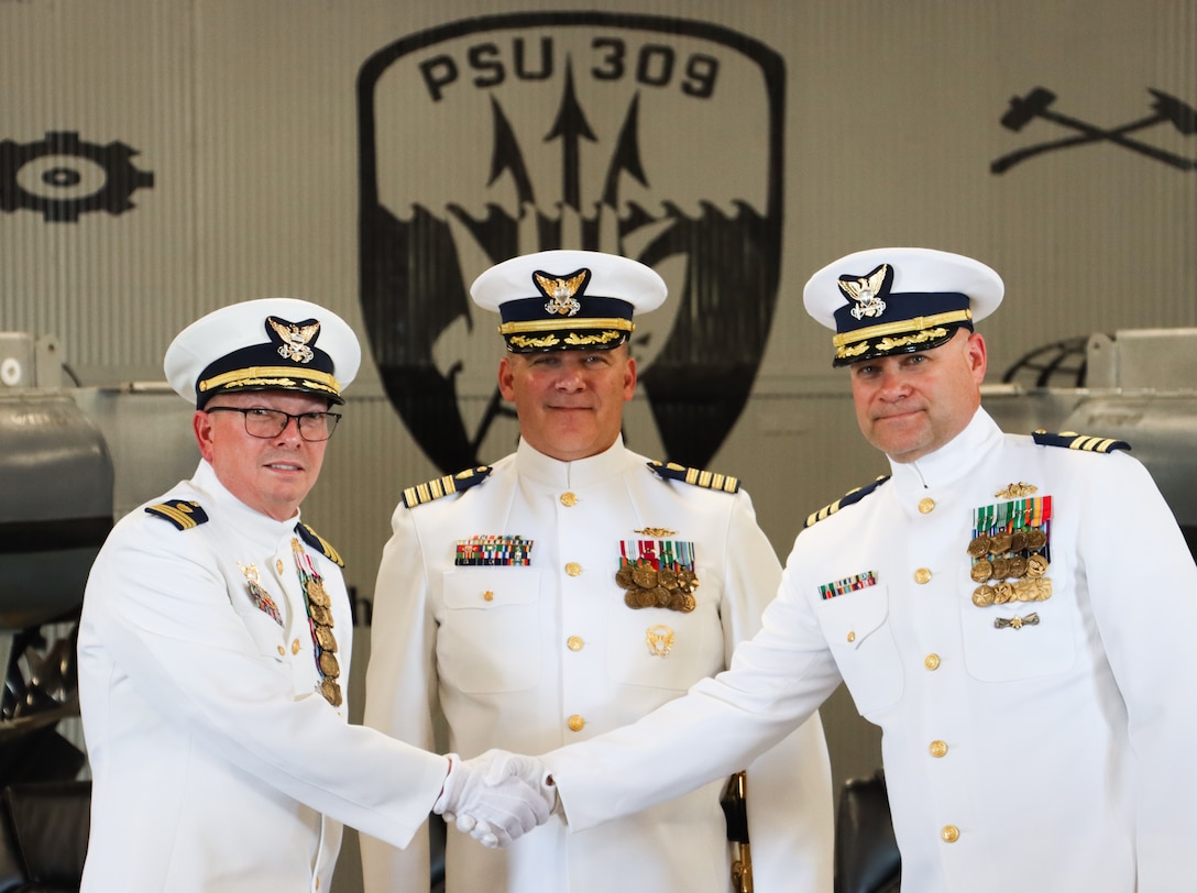 Cmdr. Todd A. Remusat (left) shakes hands and passes on command of U.S. Coast Guard Port Security Unit 309 to Cmdr. Kristopher J. Nolan (right) during the unit's change of command ceremony in Port Clinton, Ohio, Sept. 21, 2024. Capt. Jason H. Ryan (center), chief of operations, Coast Guard Pacific Area, presided over the ceremony. (U.S. Coast Guard photo by Petty Officer 2nd Class Joshua Sanchez)