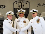Cmdr. Todd A. Remusat (left) shakes hands and passes on command of U.S. Coast Guard Port Security Unit 309 to Cmdr. Kristopher J. Nolan (right) during the unit's change of command ceremony in Port Clinton, Ohio, Sept. 21, 2024. Capt. Jason H. Ryan (center), chief of operations, Coast Guard Pacific Area, presided over the ceremony. (U.S. Coast Guard photo by Petty Officer 2nd Class Joshua Sanchez)