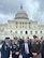 Four leaders from the Joint Task Force-National Capital Region dressed in a mix of Army uniforms and civilian attire pose for a picture in front of the U.S. Capitol building.