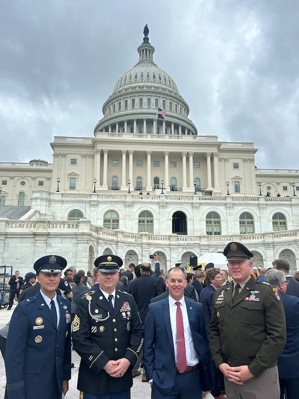 Four leaders from the Joint Task Force-National Capital Region dressed in a mix of Army uniforms and civilian attire pose for a picture in front of the U.S. Capitol building.