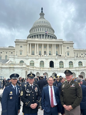 Four leaders from the Joint Task Force-National Capital Region dressed in a mix of Army uniforms and civilian attire pose for a picture in front of the U.S. Capitol building.