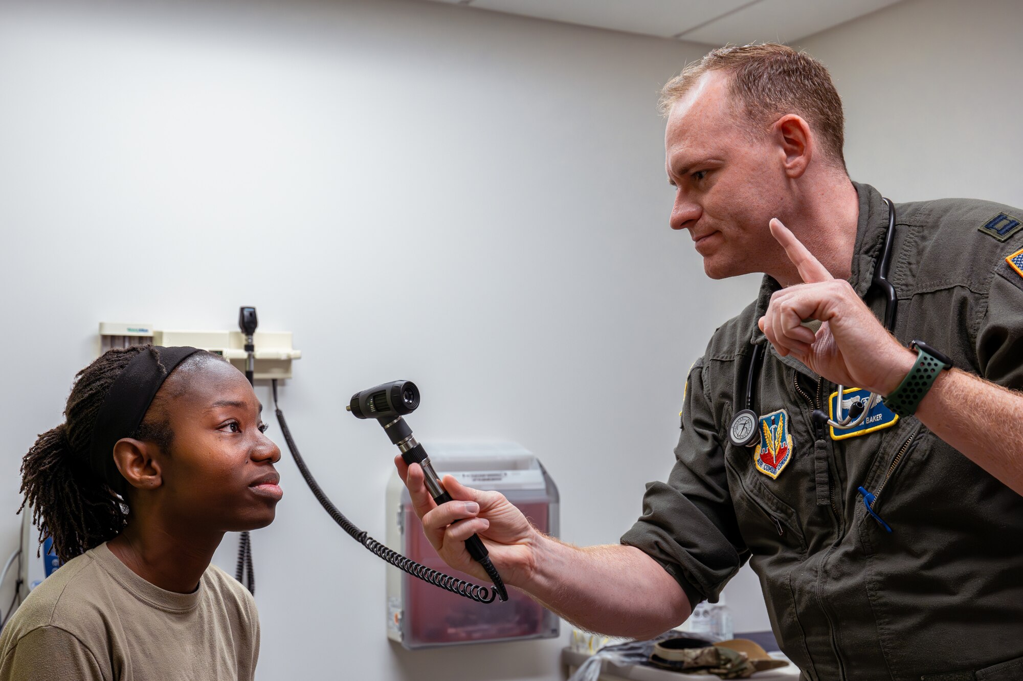 U.S. Air Force Capt. Dylan Baker, right, 325th Operational Medical Readiness Squadron flight surgeon, checks Master Sgt. Shaunita Moore’s, 325th Operations Support Squadron air traffic controller, eyes during her appointment