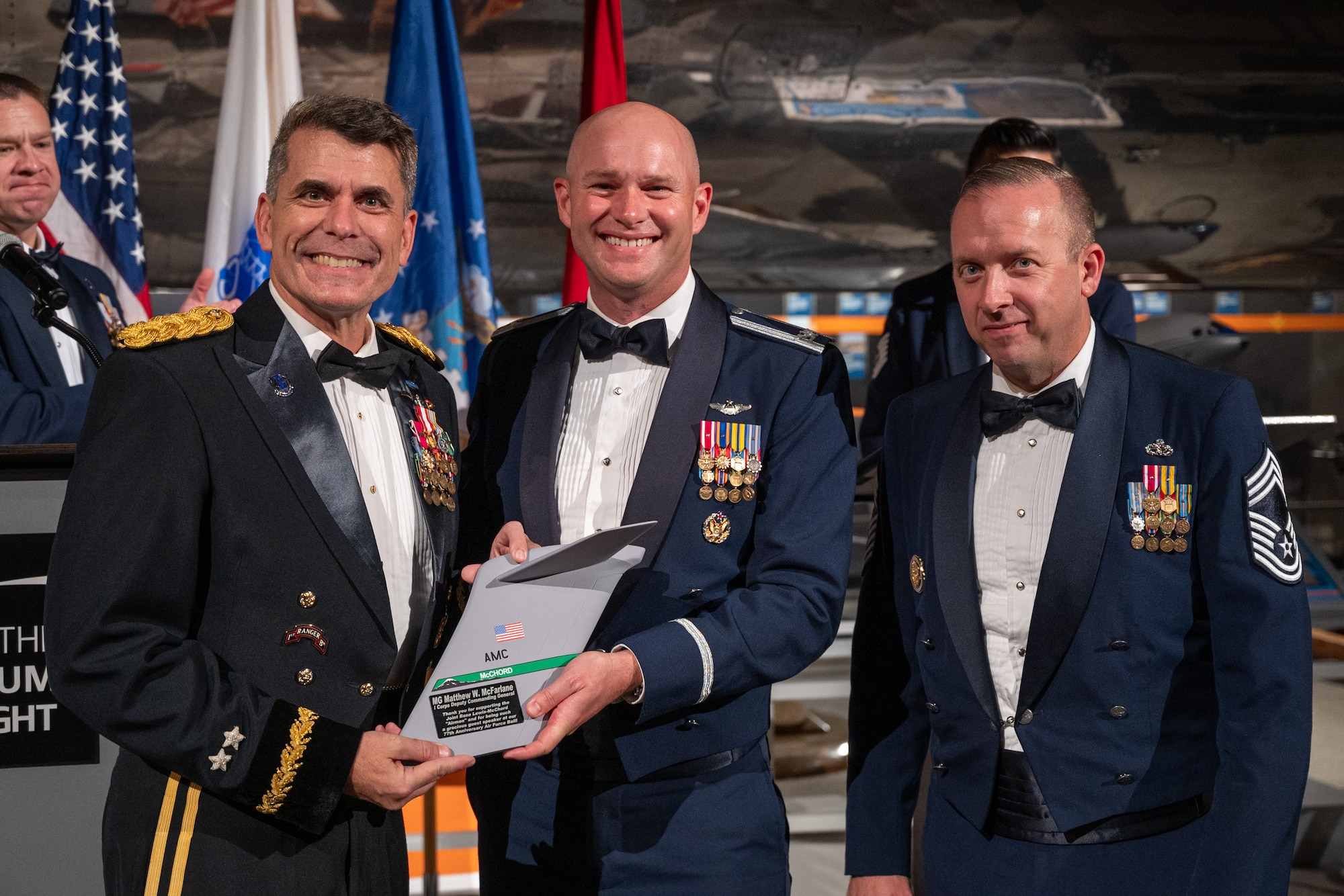 U.S. Air Force Col. John Berger, 62d Airlift Wing acting commander, center, and Chief Master Sgt. Derek Hirshfield, 62d AW acting command chief, right, present U.S. Army Maj. Gen. Matthew McFarlane, deputy commanding general of America’s First Corps, with a plaque during the 2024 Team McChord Air Force Ball in Tukwila, Washington, Sept. 20, 2024.