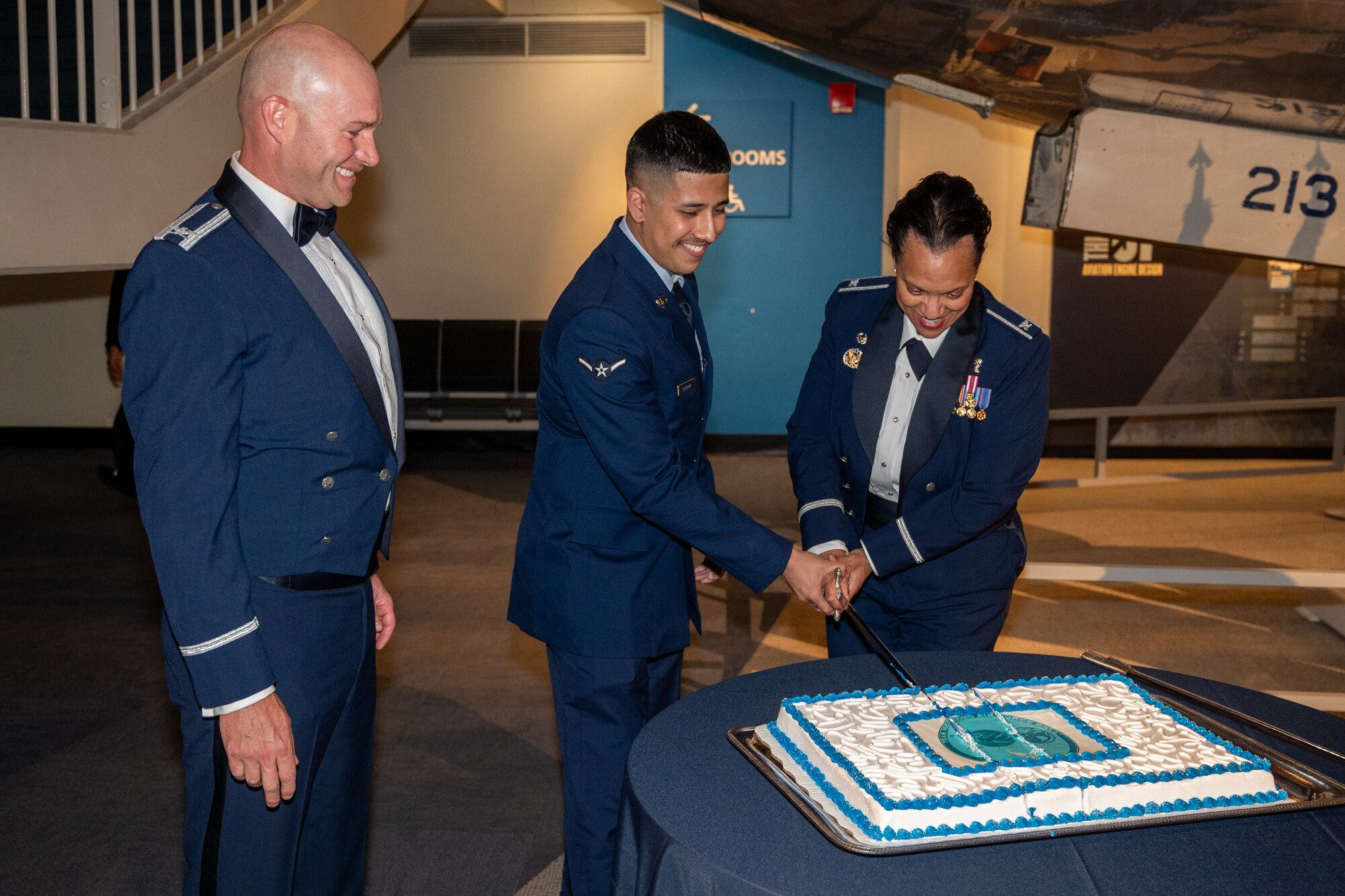 U.S. Air Force Col. John Berger, 62d Airlift Wing acting commander, left, watches Col. Karen Bowman, 62d Medical Squadron commander, right, and Airman Roland Verdugo, 62d Aircraft Maintenance Squadron journeyman, center, cut the 2024 Team McChord Air Force Ball cake during the celebration at the Seattle Museum of Flight in Tukwila, Washington, Sept. 20, 2024.