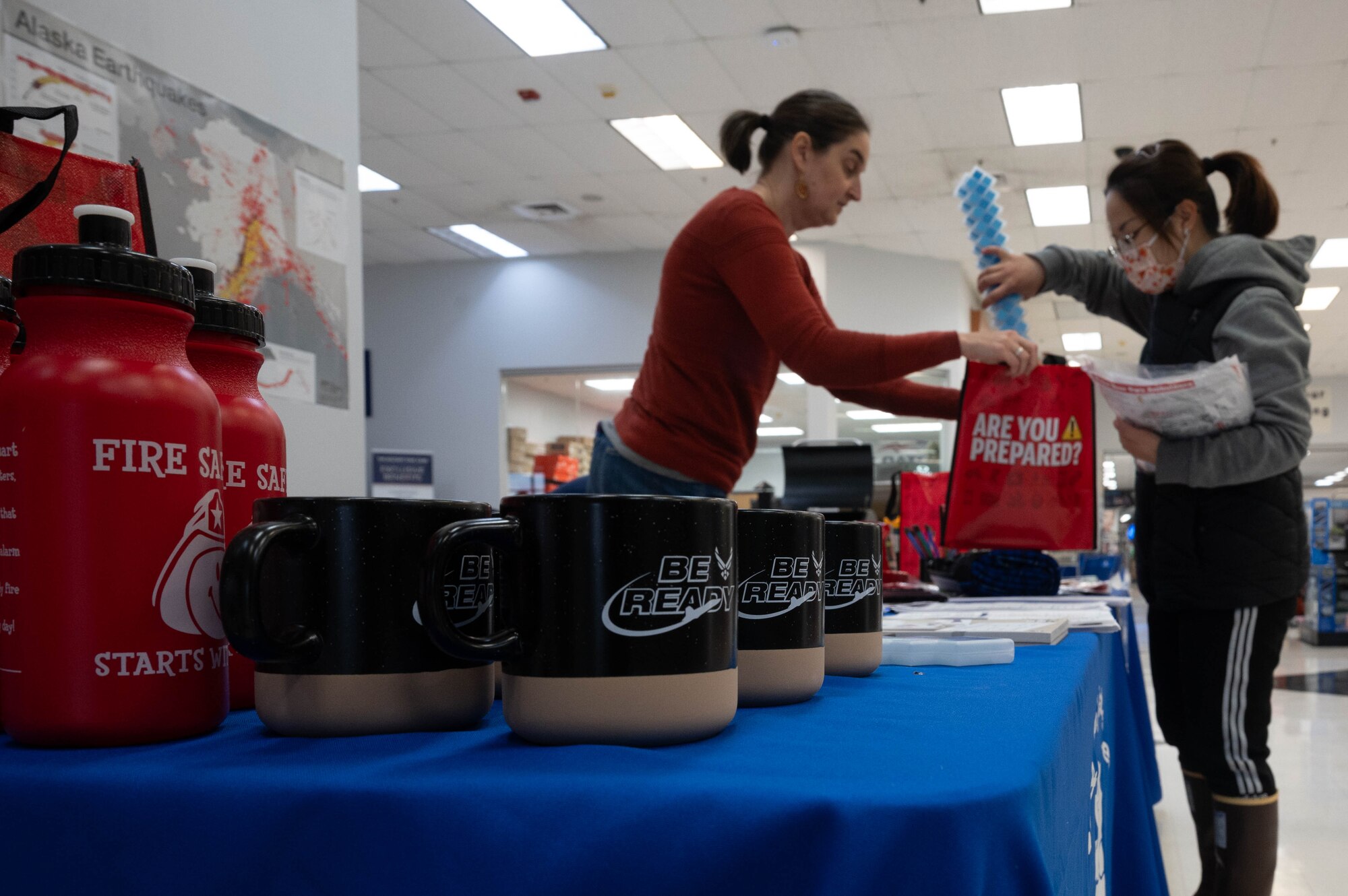 Elizabeth Nadin, Alaska Earthquake Center communications manager, hands out information and gifts about disaster preparation to a base resident at Eielson Air Force Base, Alaska, Sept. 19, 2024.