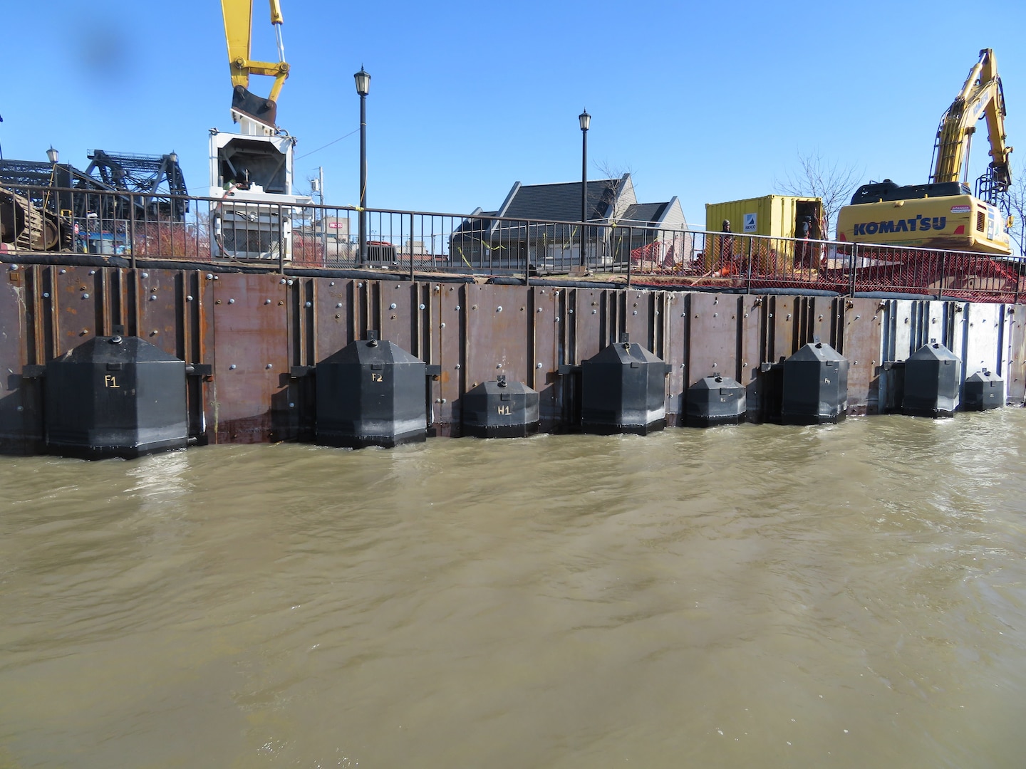 Metal baffles on a seawall along a park with construction equipment above