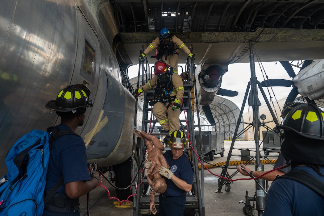 Firefighters retrieve a mannequin from a confined space in a C-130 wing cavity