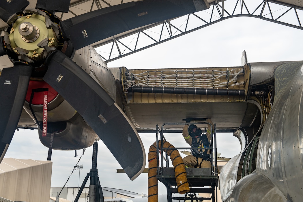 Firefighters retrieve a mannequin from a confined space in a C-130 wing cavity