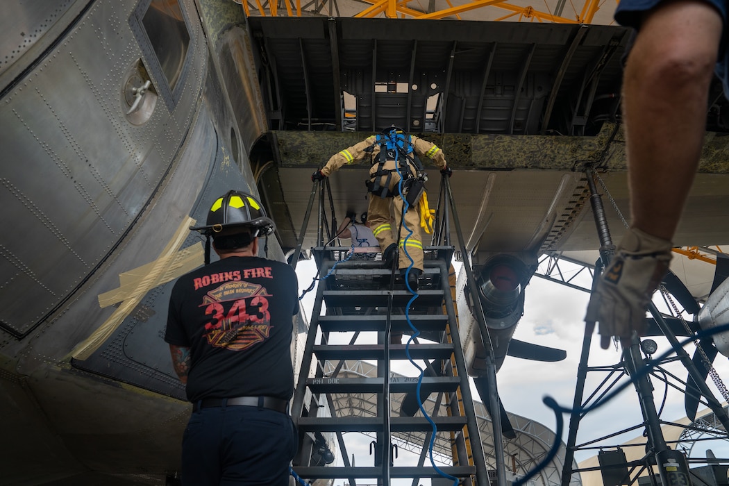 Firefighters retrieve a mannequin from a confined space in a C-130 wing cavity