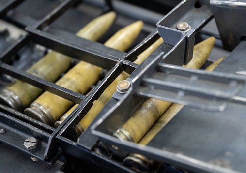 Close-up image of several ammunition rounds being loaded onto a row loading mechanism. There is a round jammed between two slots.