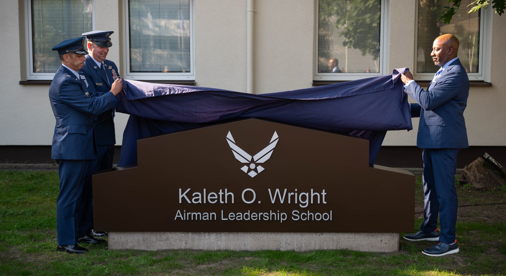 U.S. Air Force Col. Jamil I. Musa, 86th Airlift Wing deputy commander, and U.S. Air Force Chief MSgt. Louis Ludwig, 86th AW command chief, and Retired U.S. Air Force Chief Master Sergeant of the Air Force #18, Kaleth O. Wright, unveil the new Airman Leadership School sign at Kapaun Air Station, Germany, Sept. 19, 2024. The Airman Leadership School was renamed in honor of Wright, who served there as an instructor. (U.S. Air Force Photo by Senior Airman Jared Lovett)