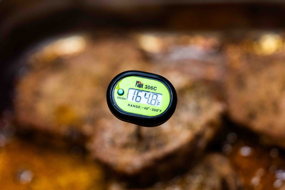 A meat thermometer shows the temperature of a beef steak.