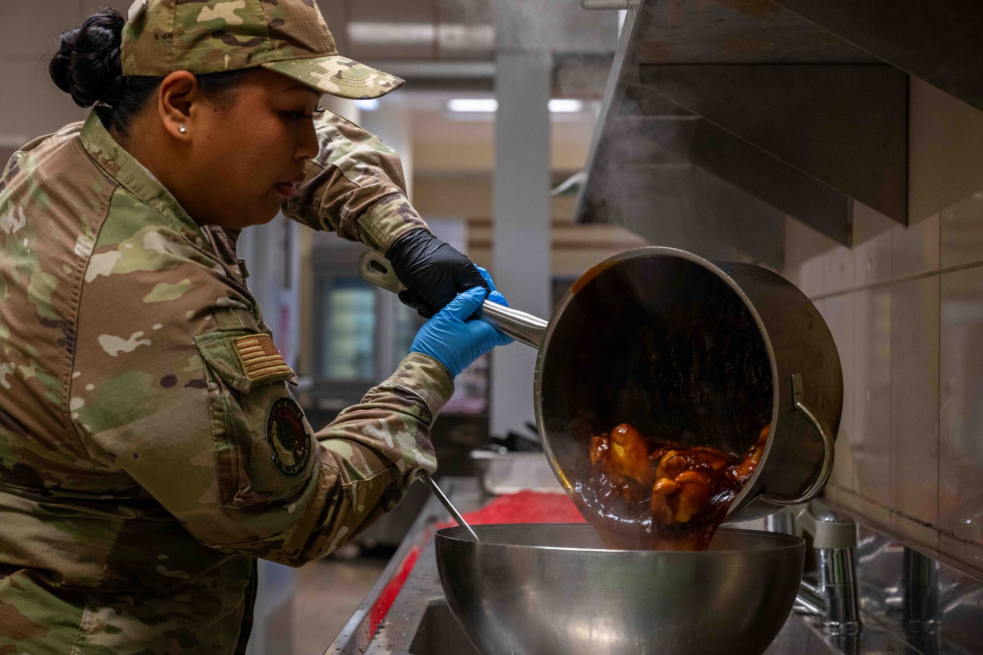 An Iron Chef competition competitor pours chicken into a pan.