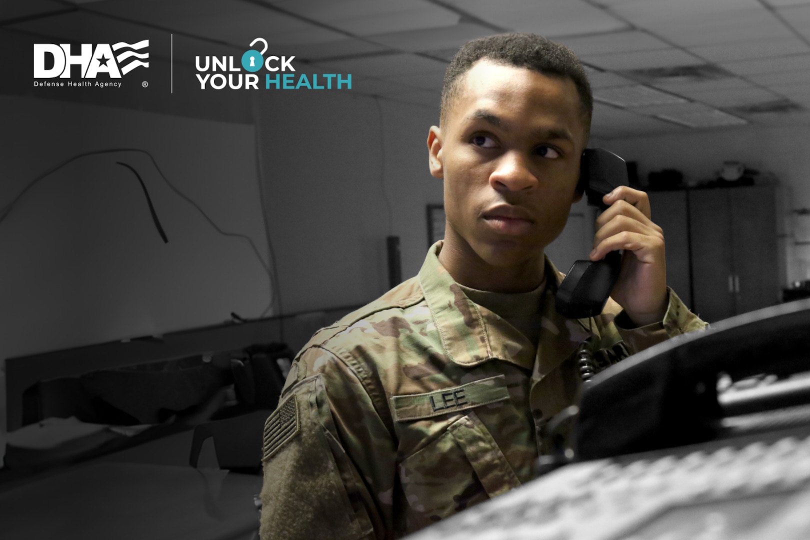 Uniformed service member stands in office and answers landline phone.