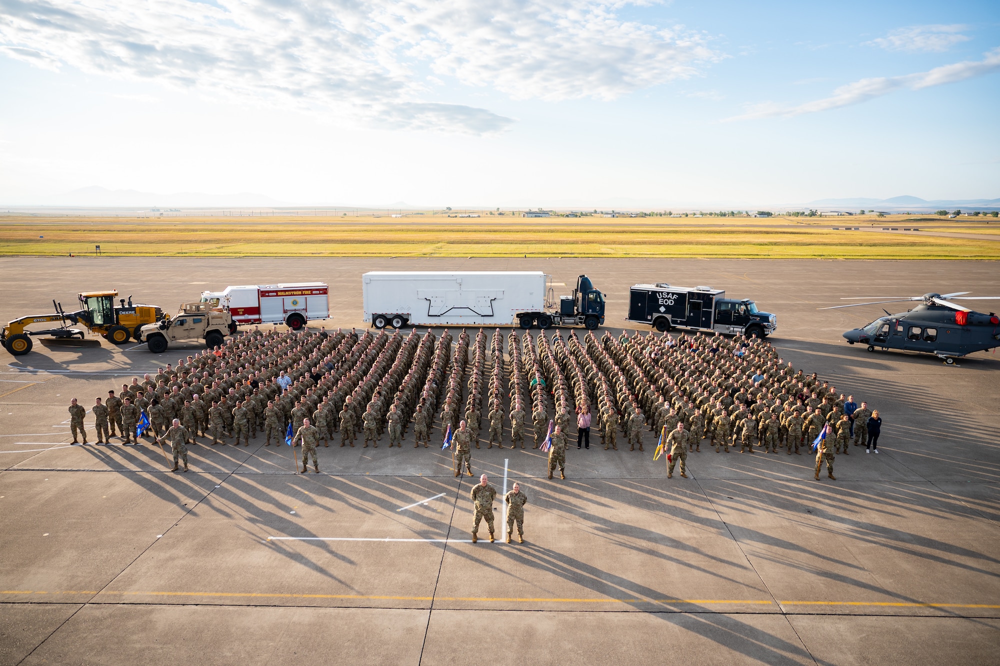 A group of uniformed personnel stand in formation for a photo.