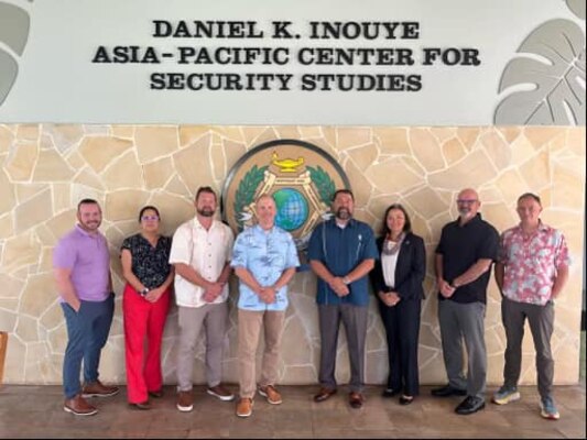 Director Lopez poses with members of PACOM in front of a building.