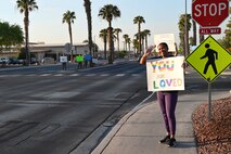 Chief Master Sgt. Adrienne Warren, the 99th Air Base Wing command chief greets drivers during a Suicide Prevention Awareness Month