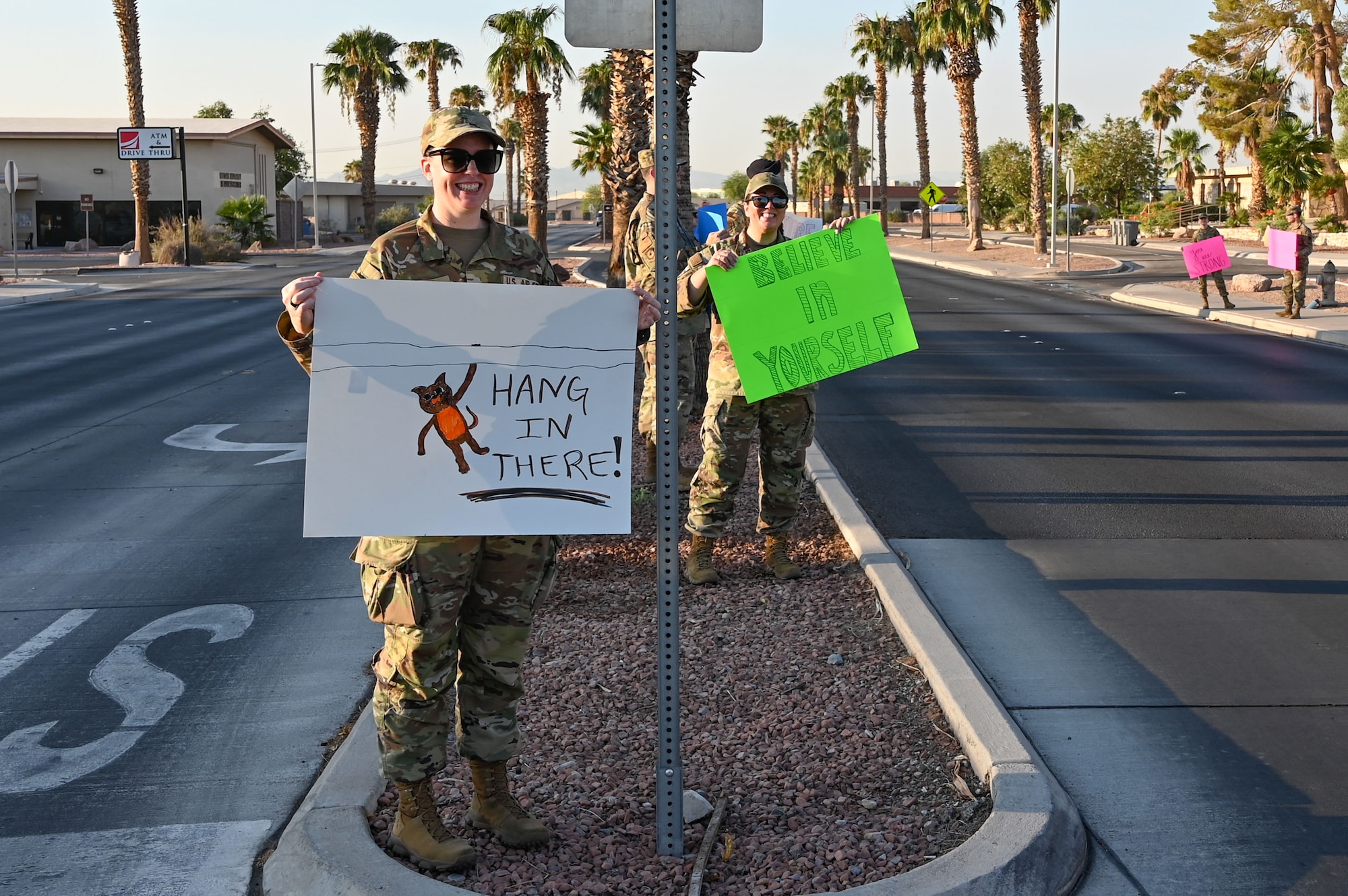 Airmen greet drivers with signs and smiles during a Suicide Prevention Awareness Month base wave-in