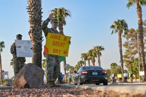 Airmen wave to drivers while holding encouraging signs during a Suicide Prevention Awareness Month base wave-in