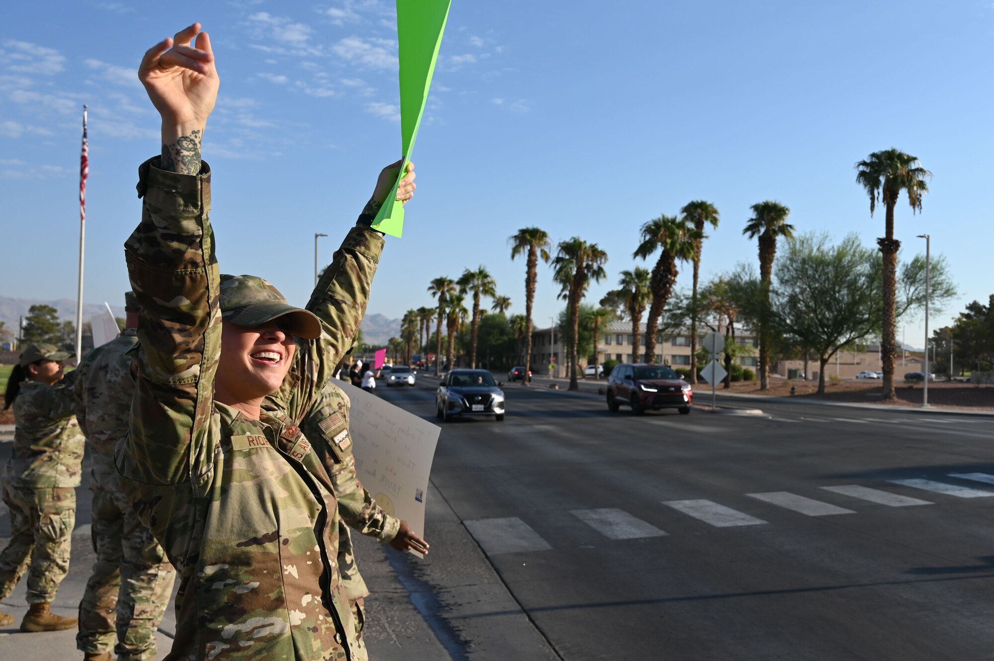 Airmen wave to drivers while holding encouraging signs during a Suicide Prevention Awareness Month base wave-in