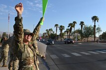 Airmen wave to drivers while holding encouraging signs during a Suicide Prevention Awareness Month base wave-in
