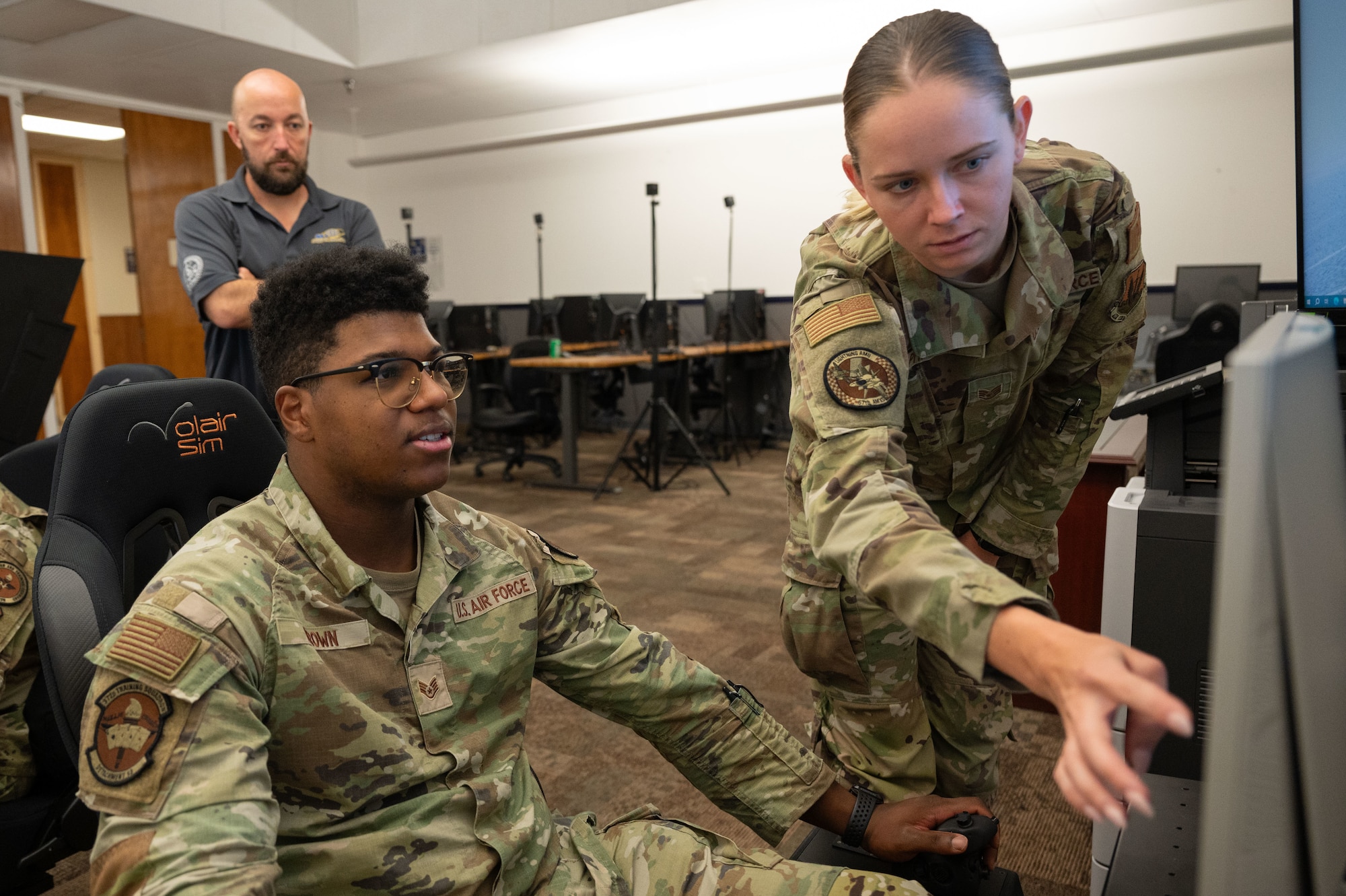Three people in an F-35 simulator class