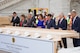 Seven members of Congress are holding hammers and driving nails into a plank of wood. There is sign in front of them that reads First Nail Ceremony.