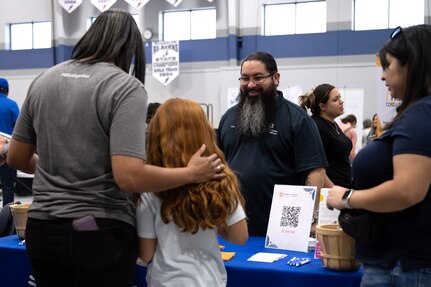 vendors are speaking with a mom and daughter at a table