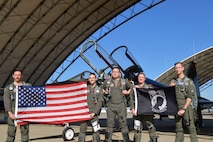 U.S. Air Force 1st Reconnaissance Squadron pilots pose with the U.S. and POW/MIA flag in front of a T-38 Talon at Beale Air Force Base, California, Sept 11, 2024.