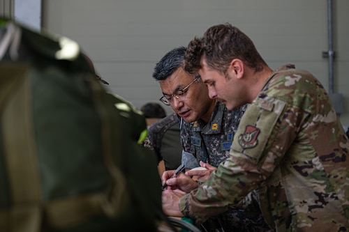 A U.S. Air Force Airman and ROK Air Force Airman inspecting cargo