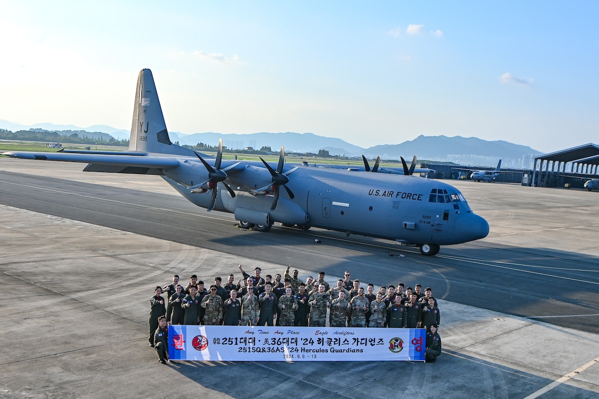 A group of US and ROK Airmen taking a photo in front of a C-130.
