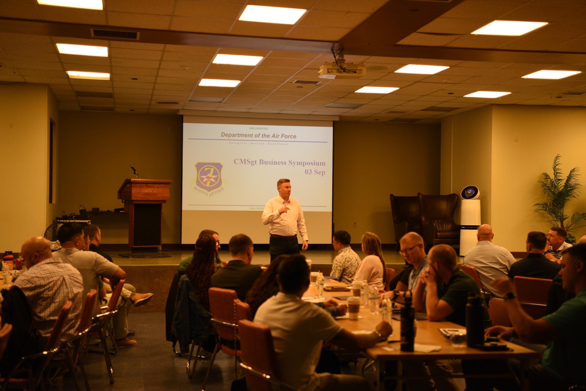 Chief Master Sergeant Jeremiah Ross, standing in front of the room a room of chief master sergeants in civilian clothes,  during the Chief Master Sergeant Business Symposium held at Osan Air Base in the Republic of Korea on September 3, 2024. The symposium provided chiefs with a setting to discuss difficult topics with a network of their peers. This is the second time the symposium has been held. (U.S. Air Force photo by Master Sgt. Rachelle Coleman)