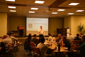 Chief Master Sergeant Jeremiah Ross, standing in front of the room a room of chief master sergeants in civilian clothes,  during the Chief Master Sergeant Business Symposium held at Osan Air Base in the Republic of Korea on September 3, 2024. The symposium provided chiefs with a setting to discuss difficult topics with a network of their peers. This is the second time the symposium has been held. (U.S. Air Force photo by Master Sgt. Rachelle Coleman)