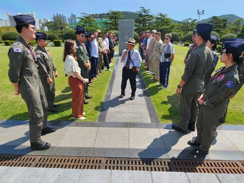 A group of US and ROK Air Force members around a monument at the United Nations Memorial Cemetery