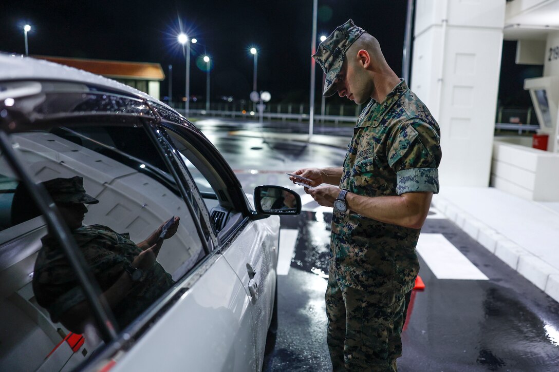 U.S. Marine Corps 1st Lt. Aivree Kamalzadeh, SYSCON communications officer, with 31st Marine Expeditionary Unit verifies liberty cards and driving documents of drivers on Camp Hansen, Okinawa, Japan, July 19, 2024.