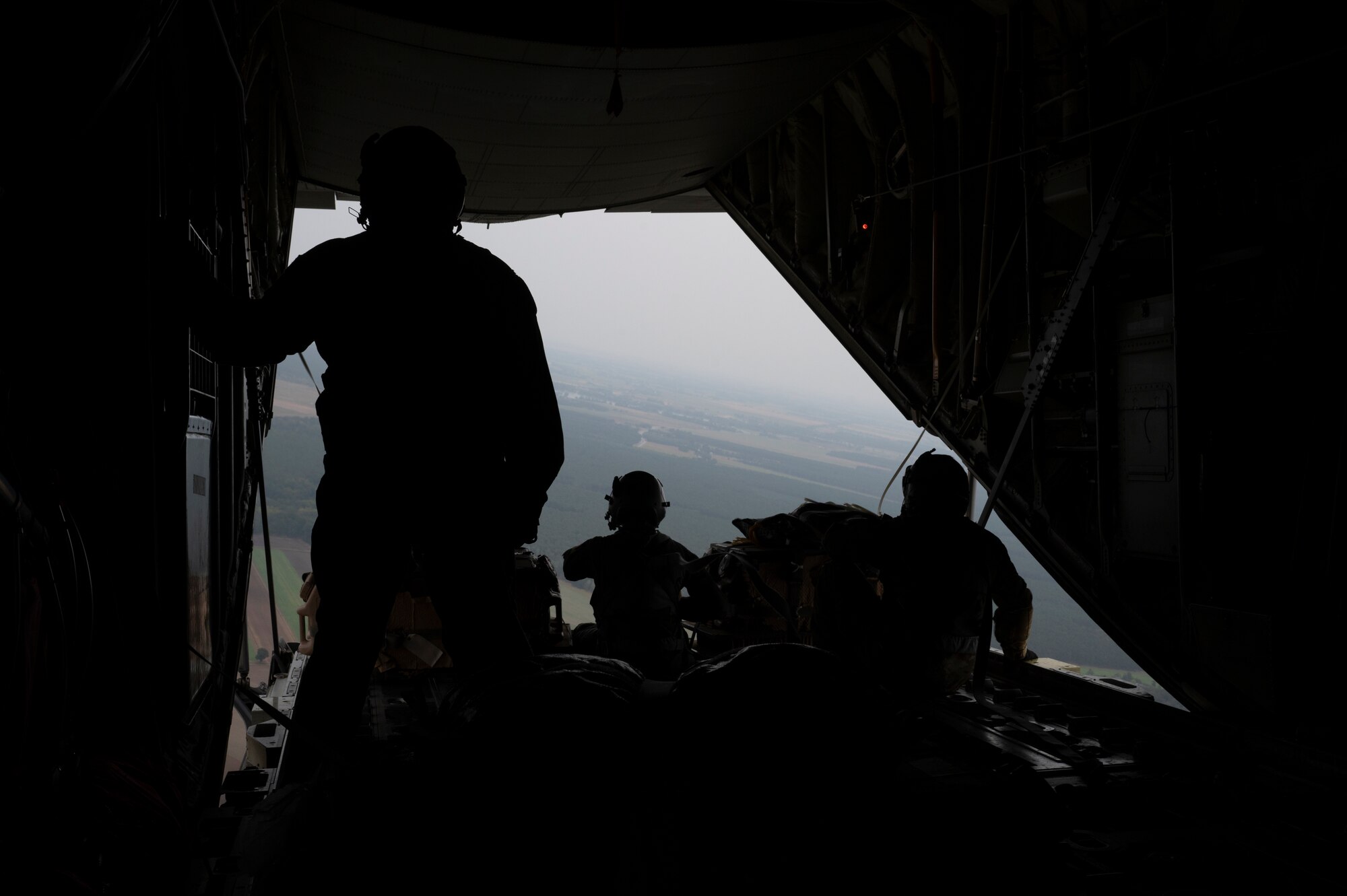 Three men prepare to drop a bundle out of a plane