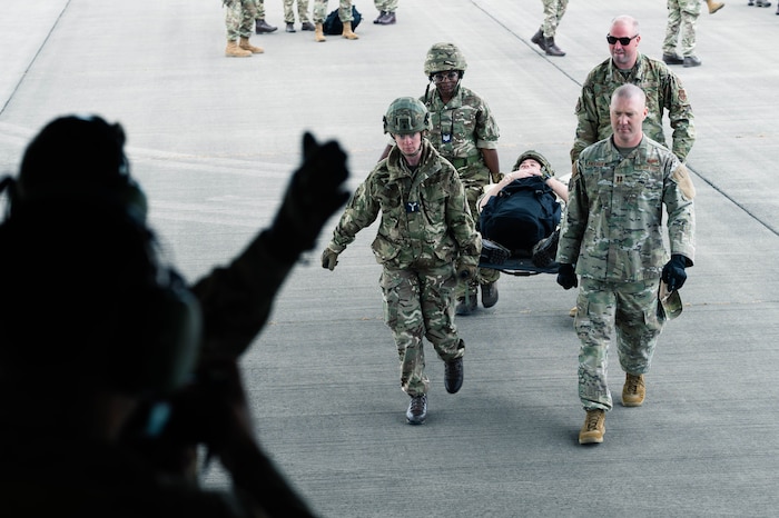 Four medical personnel consisting of the 911th Aeromedical Evacuation Squadron and Royal Auxiliary Air Force 612 Squadron carry a litter patient  from the right side of the frame aboard a C-17 Globemaster III
