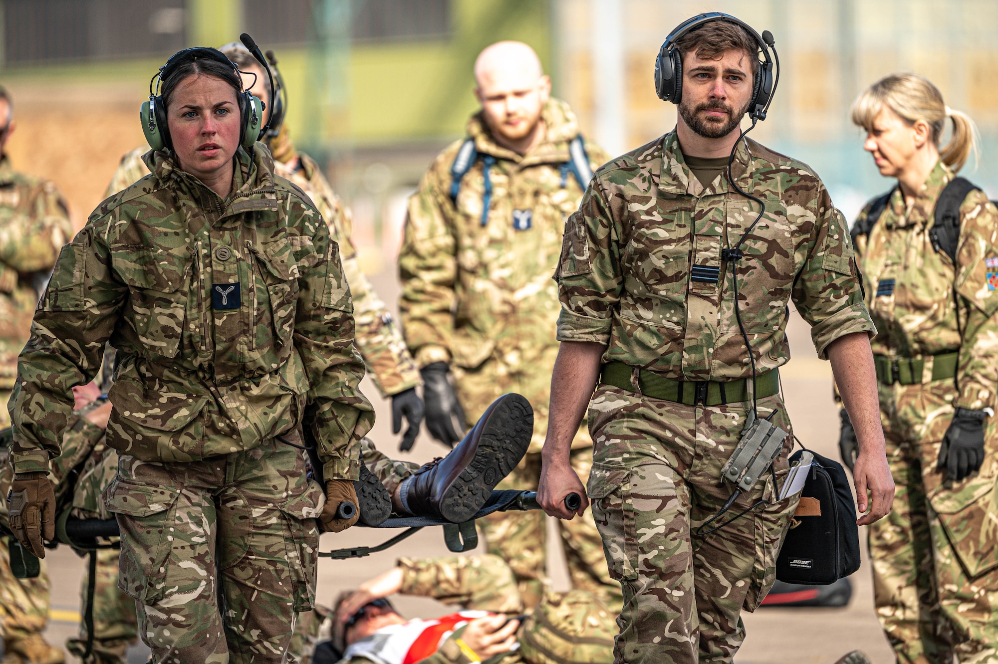Two Royal Auxiliary Air Force 612 Squadron medical members carry a patient litter behind them with other 612 Sqd personnel and 911th Aeromedical Evacuation Squadron Steel Airmen in the background