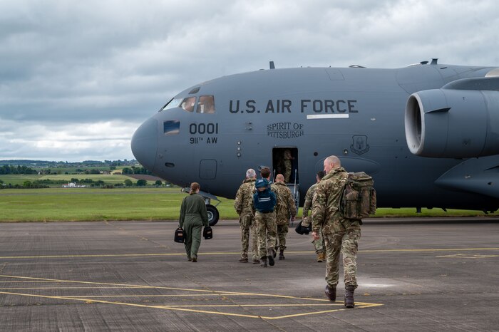 Airmen from the 911th Aeromedical Evacuation Squadron and Royal Auxiliary Air Force 612th Squadron walk toward a C-17 Globemaster III sitting in the background of the photo