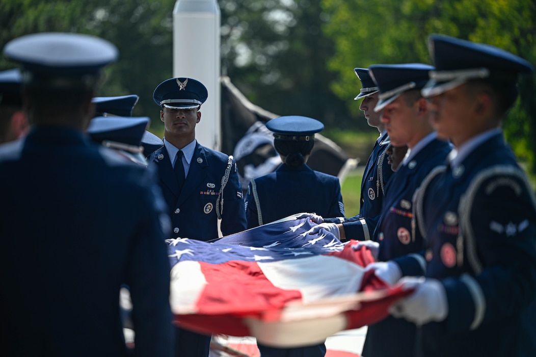 Uniformed personnel hold a U.S. flag during a ceremony.