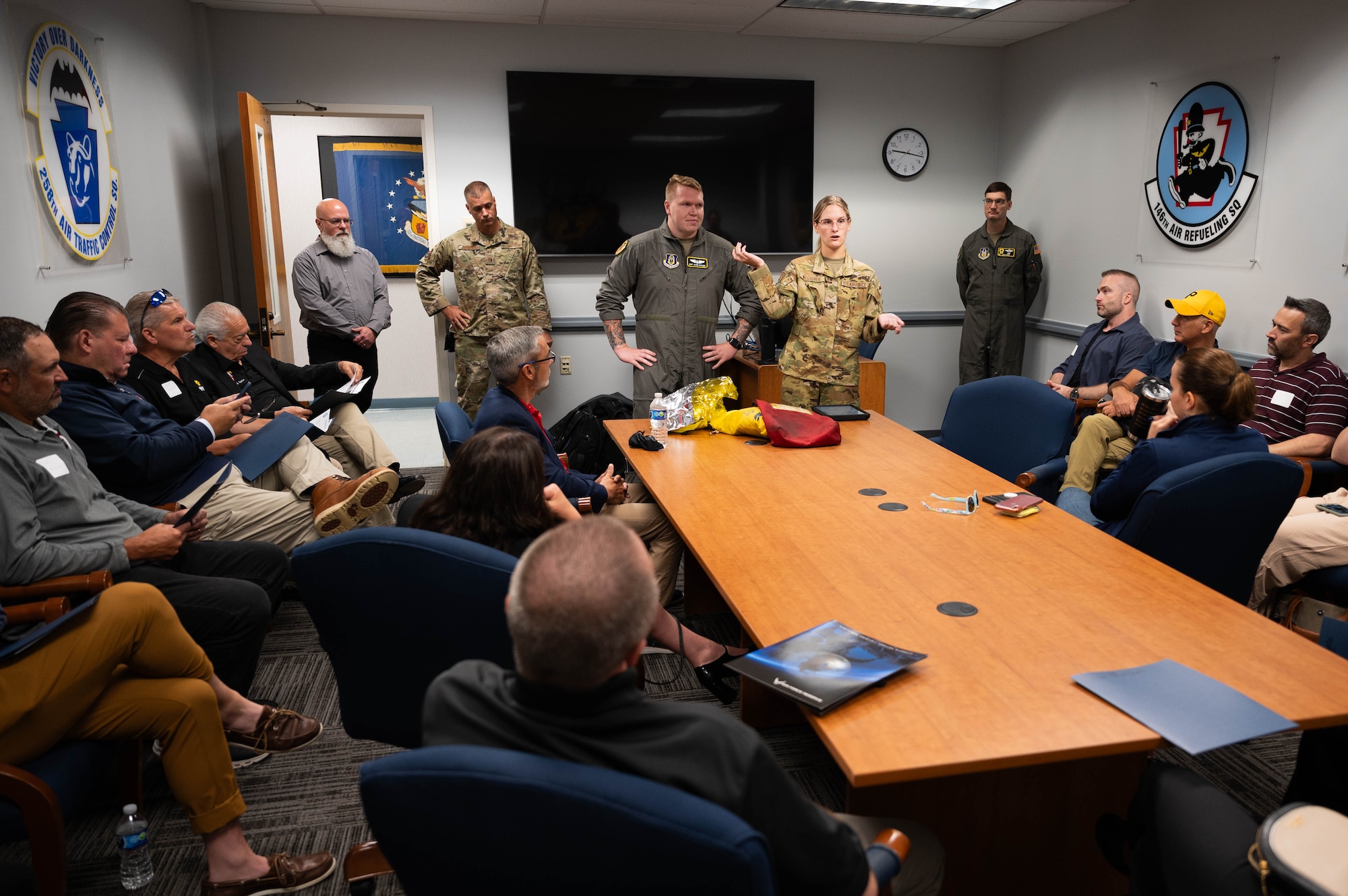 Staff Sgt. Jacob Anthony and Senior Airman Dorey Westover, provide a pre-flight safety brief to the newest Steel City Honorary Commanders Association at the front of a conference table