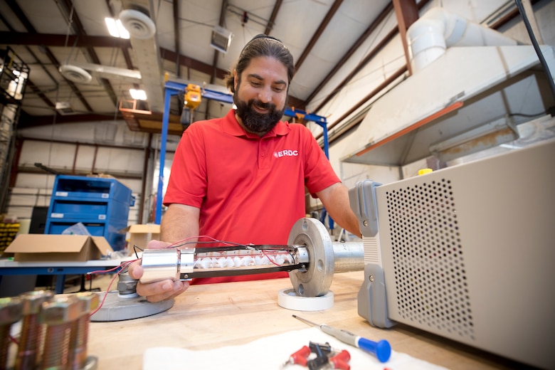 Jose Mattei-Sosa, a chemical engineer in the Environmental Laboratory, slides a quartz tube containing titanium dioxide/PLA static mixers (known as 3D Printed Photocatalytic Oxidation Devices), into a testing rig at the Environmental Laboratory, July 17.